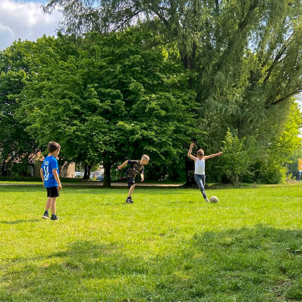 Kids spielen Fussball auf der grünen Wiese auf dem Außengelände der Freien Schule Essen e.V.